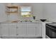 Clean kitchen with white cabinets, countertops, natural light, and floating shelves at 301 Kingston S St, St Petersburg, FL 33711