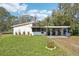 Cozy single-story home featuring a screened-in porch and carport surrounded by mature trees and a well-maintained lawn at 309 4Th Sw Ave, Ruskin, FL 33570