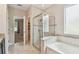 Bright bathroom featuring a glass shower, soaking tub, and neutral tile at 3530 Brook Crossing Dr, Brandon, FL 33511