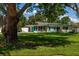 Well-kept single-story home with a lush green lawn, mature trees, and charming exterior design at 3700 56Th N St, St Petersburg, FL 33710