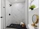 This remodeled walk-in shower features sleek marble-look tile and black hexagonal flooring at 4112 E Ellicott St, Tampa, FL 33610