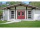 Close-up of a home's entrance featuring an eye-catching red double door and manicured lawn at 8610 Fish Lake Rd, Tampa, FL 33619