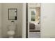 Bathroom with a toilet and a glimpse into a cozy bedroom with natural light, neutral tones, and plush bedding at 9360 Gladsome Dr, Land O Lakes, FL 34637