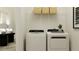 Well-lit laundry room featuring modern washer and dryer with wire shelving and decorative baskets at 9360 Gladsome Dr, Land O Lakes, FL 34637
