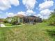 A view of the backyard, screened pool, and surrounding landscaped backyard with a tile roof at 1014 Stella Vara Dr, Lutz, FL 33548