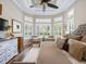Beautiful bedroom with tray ceiling, wood floors, and sitting area by bright windows at 1014 Stella Vara Dr, Lutz, FL 33548