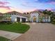 Stunning home at dusk with a clay tile roof, lush landscaping, and a spacious brick driveway at 1014 Stella Vara Dr, Lutz, FL 33548