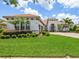 Exterior view of a white home with a clay tile roof and a lush green lawn with landscaping at 1014 Stella Vara Dr, Lutz, FL 33548