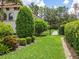 The yard is beautifully landscaped with lush, green hedges, mulch, and a stone pathway through a black gate at 1014 Stella Vara Dr, Lutz, FL 33548