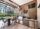 An outdoor kitchen and bar area with stainless grill, refrigerator, and a decorative stone wall at 1014 Stella Vara Dr, Lutz, FL 33548