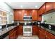 Modern kitchen featuring stainless steel appliances, granite countertops, and warm wood cabinetry at 10947 Brickside Ct, Riverview, FL 33579