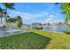 Lush lawn in the backyard leads to a canal with a private dock on a sunny day at 11240 6Th E St, Treasure Island, FL 33706