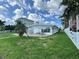 View of the backyard with lush green lawn, partial seating area, and white picket fence outlining the space at 11240 6Th E St, Treasure Island, FL 33706