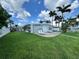 Landscaped backyard with lush green lawn, palm trees, and patio seating area, ideal for outdoor living at 11240 6Th E St, Treasure Island, FL 33706