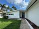 Contemporary home with a well-manicured lawn and walkway leading to the front door, framed by lush landscaping at 11240 6Th E St, Treasure Island, FL 33706