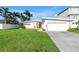 Single-story home with a manicured lawn, palm trees and a driveway leading to an attached garage at 11240 6Th E St, Treasure Island, FL 33706