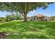 Spacious backyard with a large shade tree, enclosed sunroom, and view of the nearby pond, offering ample space at 11550 Wellman Dr, Riverview, FL 33578