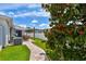 Landscaped backyard featuring a tree, well-kept lawn, brick paver walkway, and white perimeter fence at 13027 Pennybrook Dr, Riverview, FL 33579