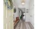 Inviting entryway features wood-look floors, bench seat, decorative mirror, and a charming floral wreath on the front door at 13027 Pennybrook Dr, Riverview, FL 33579