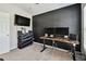 Modern home office with painted brick accent wall, sleek desk, and entertainment system at 13027 Pennybrook Dr, Riverview, FL 33579