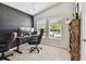 Bright home office with a modern brick wall, dual monitors, and a comfortable executive chair at 13027 Pennybrook Dr, Riverview, FL 33579