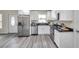 Updated kitchen featuring stainless steel appliances, white cabinetry, and gray wood-look flooring at 1561 S Martin Luther King Jr Ave, Clearwater, FL 33756