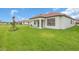 Grassy backyard showcasing a one-story house with a covered patio and tidy landscaping at 17415 Holly Well Ave, Wimauma, FL 33598
