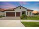 Charming single-story home featuring a tiled roof, three-car garage, and well-manicured landscaping at 17415 Holly Well Ave, Wimauma, FL 33598