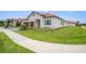 Well-maintained home featuring a tiled roof, three-car garage, and lush, green landscaping at 17415 Holly Well Ave, Wimauma, FL 33598
