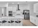 Modern kitchen showcasing stainless steel appliances, white cabinetry, an island, and stylish barstools at 17415 Holly Well Ave, Wimauma, FL 33598