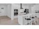 Bright kitchen featuring modern appliances, white cabinets, an island with seating, and wood flooring at 17415 Holly Well Ave, Wimauma, FL 33598