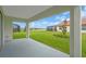 Covered patio overlooking a lush green lawn and scenic lake view with screened in lanais in the distance at 17415 Holly Well Ave, Wimauma, FL 33598