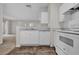 Kitchen with white appliances and cabinets, opening to the living area at 18001 Richmond Place Dr # 116, Tampa, FL 33647