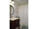 Bright bathroom features a stylish vanity with dark cabinets, round mirror, and shower with curtain at 3212 Stevenson St, Plant City, FL 33566