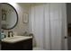 Cozy bathroom featuring a round mirror, dark cabinets, and a shower with striped curtain at 3212 Stevenson St, Plant City, FL 33566