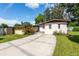 Home's front exterior with driveway, well-manicured lawn, and colorful flower bushes at 4018 E Bluff Ave, Tampa, FL 33617