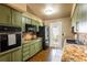 Compact kitchen with granite countertops, vintage green cabinetry, and modern appliances at 4018 E Bluff Ave, Tampa, FL 33617