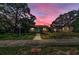 Inviting home exterior with sidewalk, landscaped yard, and mature trees under a vibrant twilight sky at 4616 5Th N Ave, St Petersburg, FL 33713
