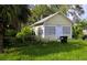 A quaint yellow single story home featuring a rectangular design, fenced yard, and overgrown lawn at 514 Woodlawn St, Clearwater, FL 33756