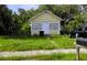 A cute yellow single story house with a traditional design, small front yard, and an overgrown lawn at 514 Woodlawn St, Clearwater, FL 33756