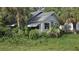 Exterior angle of a bright, white one story home showcasing tropical landscaping and a covered awning over a window at 518 Woodlawn St, Clearwater, FL 33756