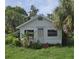 Charming single-story home nestled amongst tropical foliage, displaying a quaint exterior with bright white siding at 518 Woodlawn St, Clearwater, FL 33756