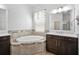 Bright bathroom featuring a soaking tub, tiled surround, dark wood vanity, and a marble countertop at 6519 Watson Rd, Riverview, FL 33578