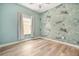 Stylish bedroom with tiger-themed wallpaper, hardwood floors, and bright natural light at 6519 Watson Rd, Riverview, FL 33578
