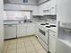 A kitchen with white cabinets, a dishwasher, and a pass through to the living room at 7148 E Bank Dr # 7148, Tampa, FL 33617