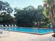 Inviting community pool with lounge chairs on a sunny day, surrounded by lush trees and a secure fence at 7148 E Bank Dr # 7148, Tampa, FL 33617