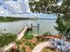 Serene backyard featuring a private dock, fire pit area, and lush greenery along the waterfront at 8 Sunset Bay Dr, Belleair, FL 33756