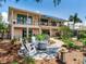 Lovely backyard with firepit, lush landscaping, stone patio, and covered balconies on a sunny day at 8 Sunset Bay Dr, Belleair, FL 33756