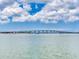 Picturesque view of a bridge over calm waters under a beautiful blue sky with fluffy clouds at 8 Sunset Bay Dr, Belleair, FL 33756