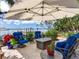 Outdoor patio with blue chairs and a sun umbrella overlooking the water at 8 Sunset Bay Dr, Belleair, FL 33756
